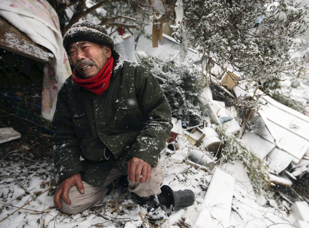 A man grieves in front of te wreckage where his mother's body was buried.